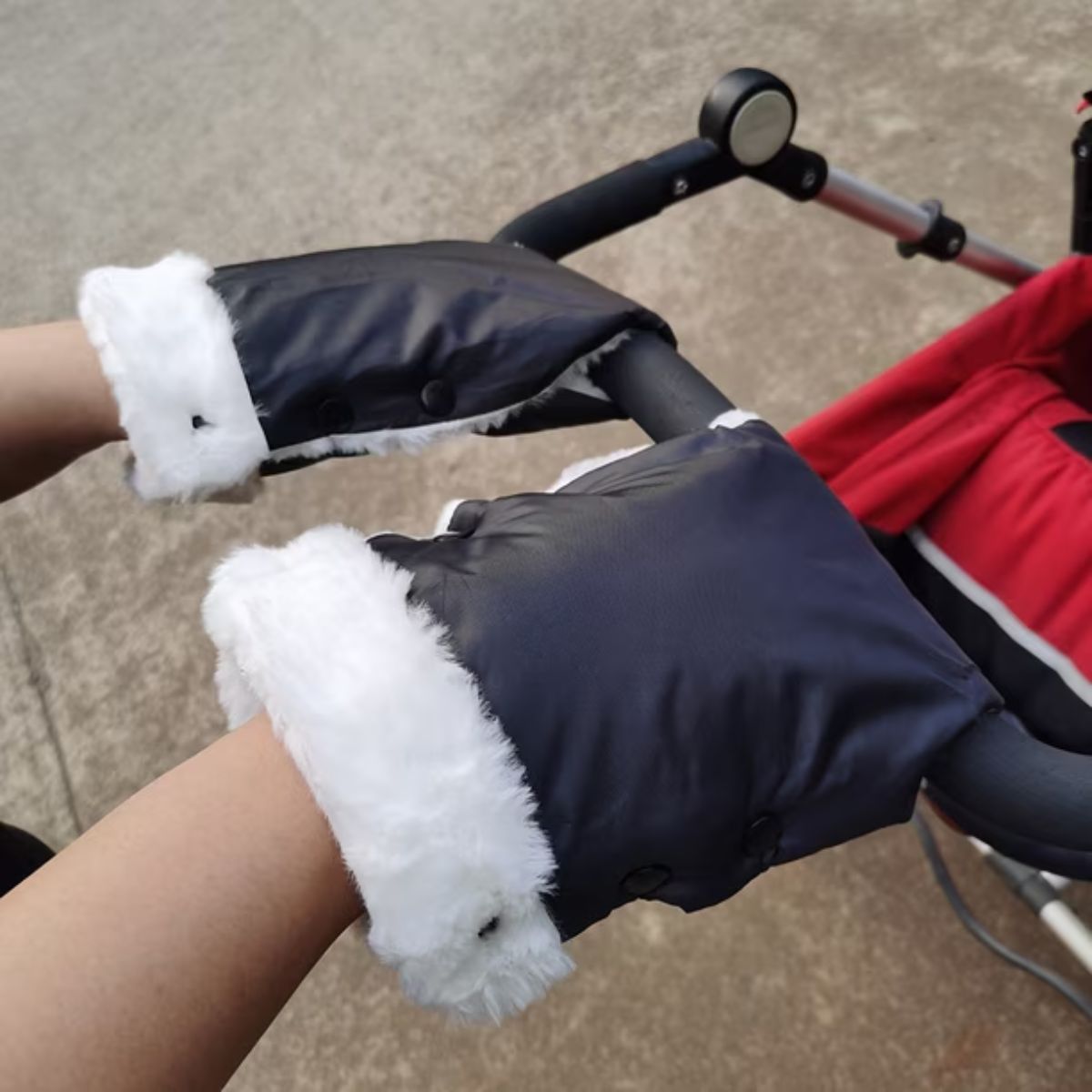 Vue de côté des gants de poussette doublés noirs avec bordure blanche épaisse, fixés au guidon par boutons-pression