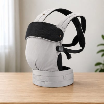 Porte bébé ventral et dorsal gris avec bretelles croisées, présenté seul sur une table