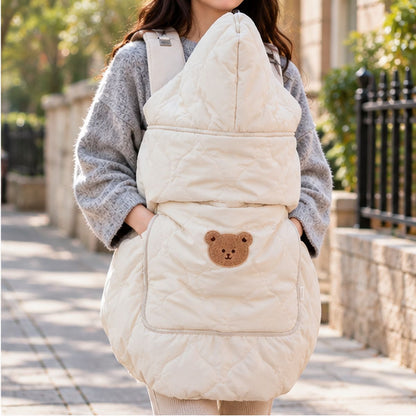 Cape porte-bébé hiver ours beige vue de face en intérieur, avec grande capuche relevée, matelassage et motif ours sur la poche.