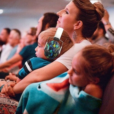 Enfant portant un casque anti-bruit bébé blanc ZenListen, confortablement installé lors d’un concert avec sa famille