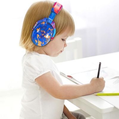 Petite fille portant un casque anti-bruit enfant bleu avec motifs orange et rouge SilenceZen, dessinant tranquillement, conçu pour améliorer la concentration et réduire les distractions sonores