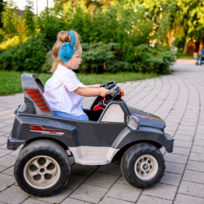 Enfant jouant avec une voiture électrique, portant un casque antibruit enfant bleu, garantissant sécurité et tranquillité pendant ses activités extérieures