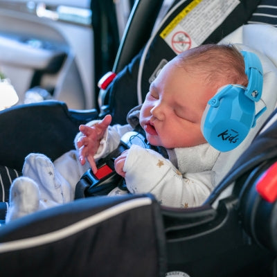 Bébé nouveau-né dans un siège auto portant un casque anti bruit enfant bleu, offrant une protection sonore douce pour les oreilles sensibles