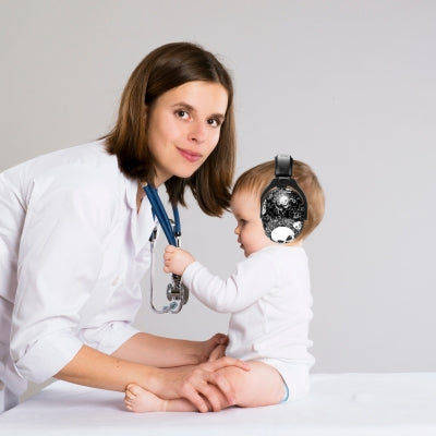 Un bébé avec un casque anti-bruit enfant SafeEars noir, parfait pour le confort et la sérénité lors d'une visite chez le médecin