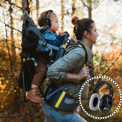 Un enfant dans un sac à dos de randonnée, équipé d’un casque antibruit enfant noir SilenceAnge, offrant une protection idéale pour explorer en toute sécurité