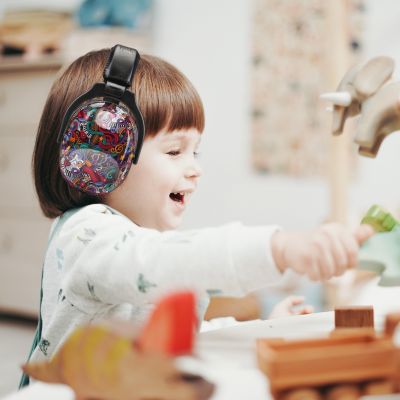 Enfant portant un casque anti-bruit enfant noir avec motifs musicaux multicolores SilenceZen, jouant avec des blocs dans un environnement calme, idéal pour améliorer leur focus et réduire les distractions