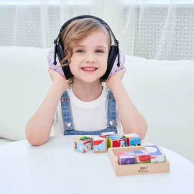 Petite fille portant un casque anti bruit enfant rose avec motifs licornes, jouant calmement avec des blocs de construction tout en restant protégée du bruit