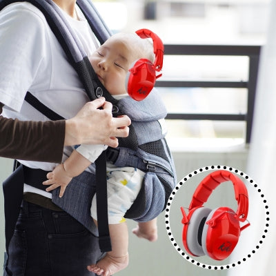 Un bébé endormi dans un porte-bébé, protégé par un casque antibruit enfant rouge SilenceAnge, assurant un confort optimal lors des déplacements