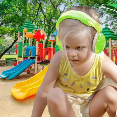 Enfant jouant dans un parc avec un casque antibruit enfant vert, réduisant efficacement les nuisances sonores pour une expérience calme