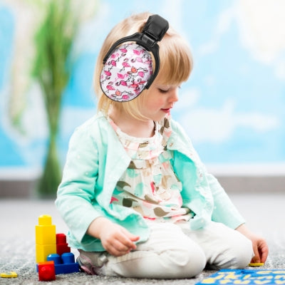 Bébé jouant avec des jouets éducatifs dans une salle de jeux, portant un casque anti bruit enfant violet galaxie, conçu pour encourager la créativité tout en protégeant son audition