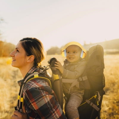 Bébé portant un casque antibruit pour bébé jaune lors d'une balade en plein air, assurant confort et protection sonore