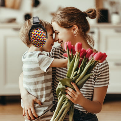 Mère et enfant partageant un moment chaleureux, l'enfant portant un casque antibruit enfant OudiZen avec un motif puzzle multicolore, assurant sécurité et confort