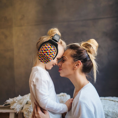 Mère et fille profitant d’un moment de tendresse, la fille portant un casque antibruit enfant au design puzzle multicolore, entièrement ajustable et confortable