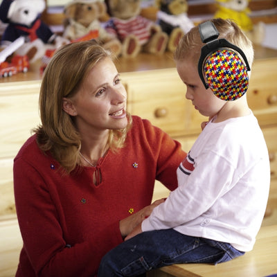 Un garçon portant un casque antibruit enfant au design puzzle multicolore, idéal pour les activités scolaires ou les moments de calme à la maison