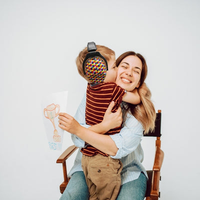 Mère et enfant dans un moment de câlin, l’enfant portant un casque antibruit enfant avec un motif puzzle multicolore, conçu pour un confort optimal et une protection auditive