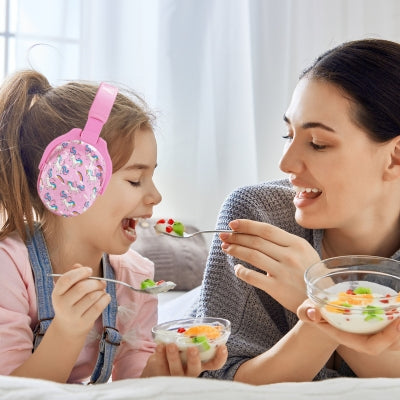 Mère et fille dégustant un dessert, la fille portant un casque antibruit enfant rose avec motifs de licornes, offrant confort et tranquillité lors des moments en famille