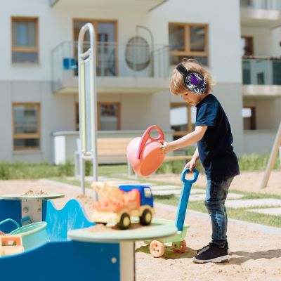 Enfant jouant dans un bac à sable, protégé des nuisances sonores avec un casque antibruit VioletEdge violet, offrant un ajustement parfait et sécurisé pour les activités en extérieur