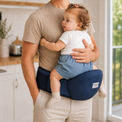 Ceinture porte bebe bleu marine avec tabouret de hanche, enfant face au porteur dans une cuisine