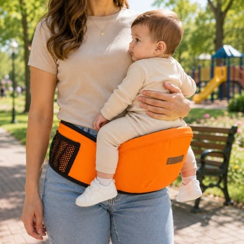 Ceinture porte bebe orange avec tabouret de hanche, enfant face au porteur dans un parc