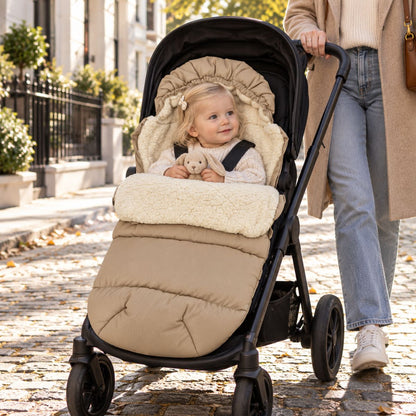 Chancelière avec capuche beige et doublure sherpa installée sur une poussette en promenade