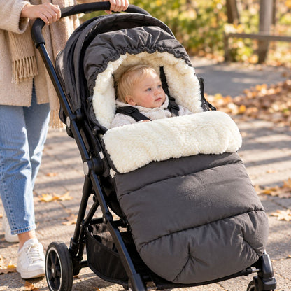 Chancelière avec capuche gris foncé et doublure sherpa installée sur une poussette en promenade