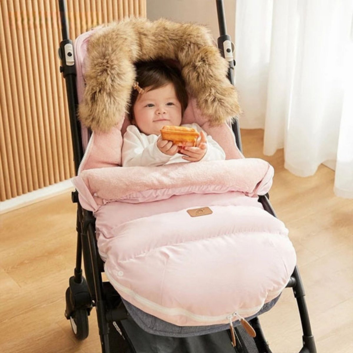 bébé souriant installé dans chanceliere bebe rose pale, capuche chaude et douce