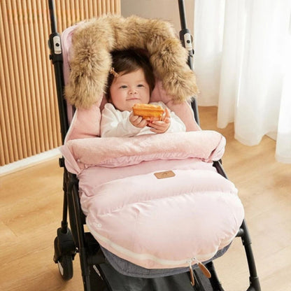 bébé souriant installé dans chanceliere bebe rose pale, capuche chaude et douce