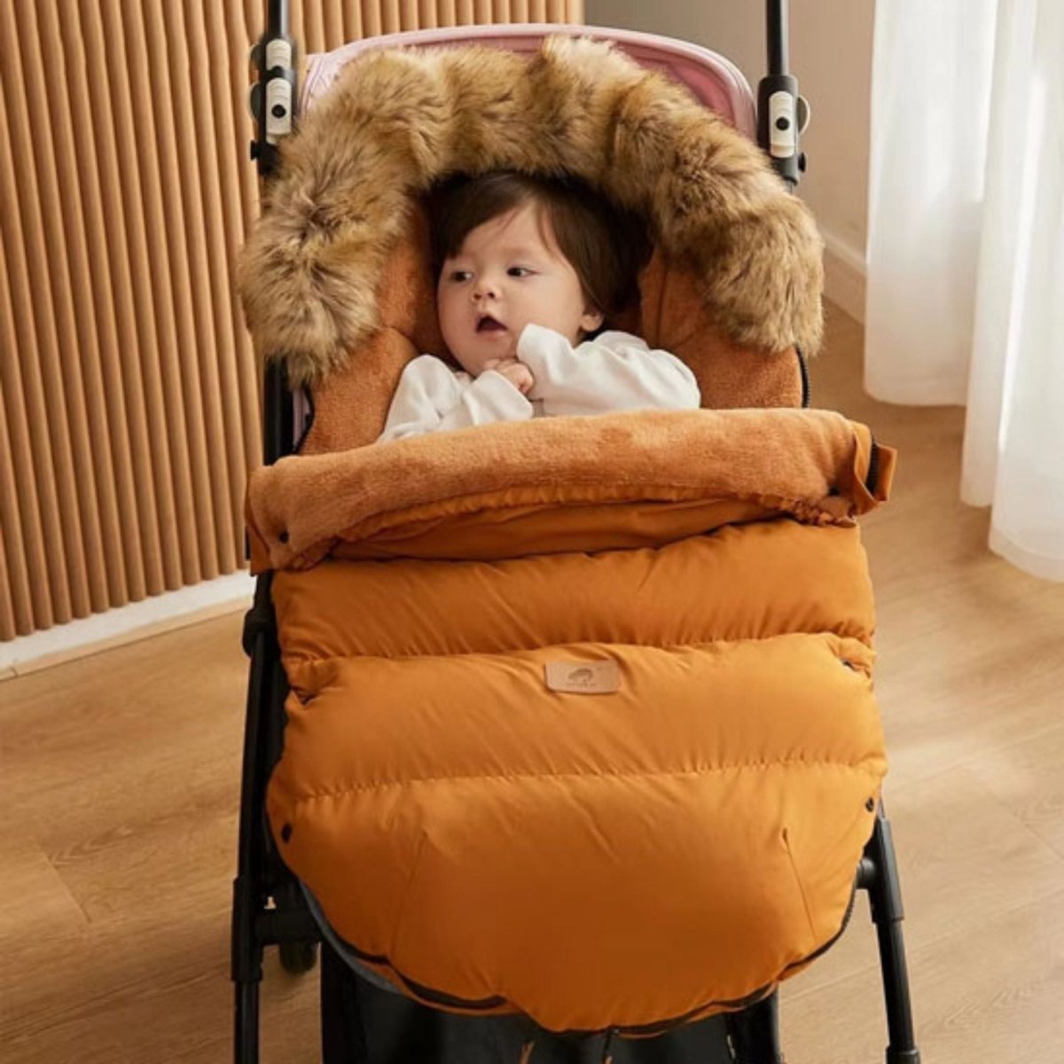 chanceliere bebe marron en situation, bébé éveillé dans une poussette beige, capuche fourrure relevée