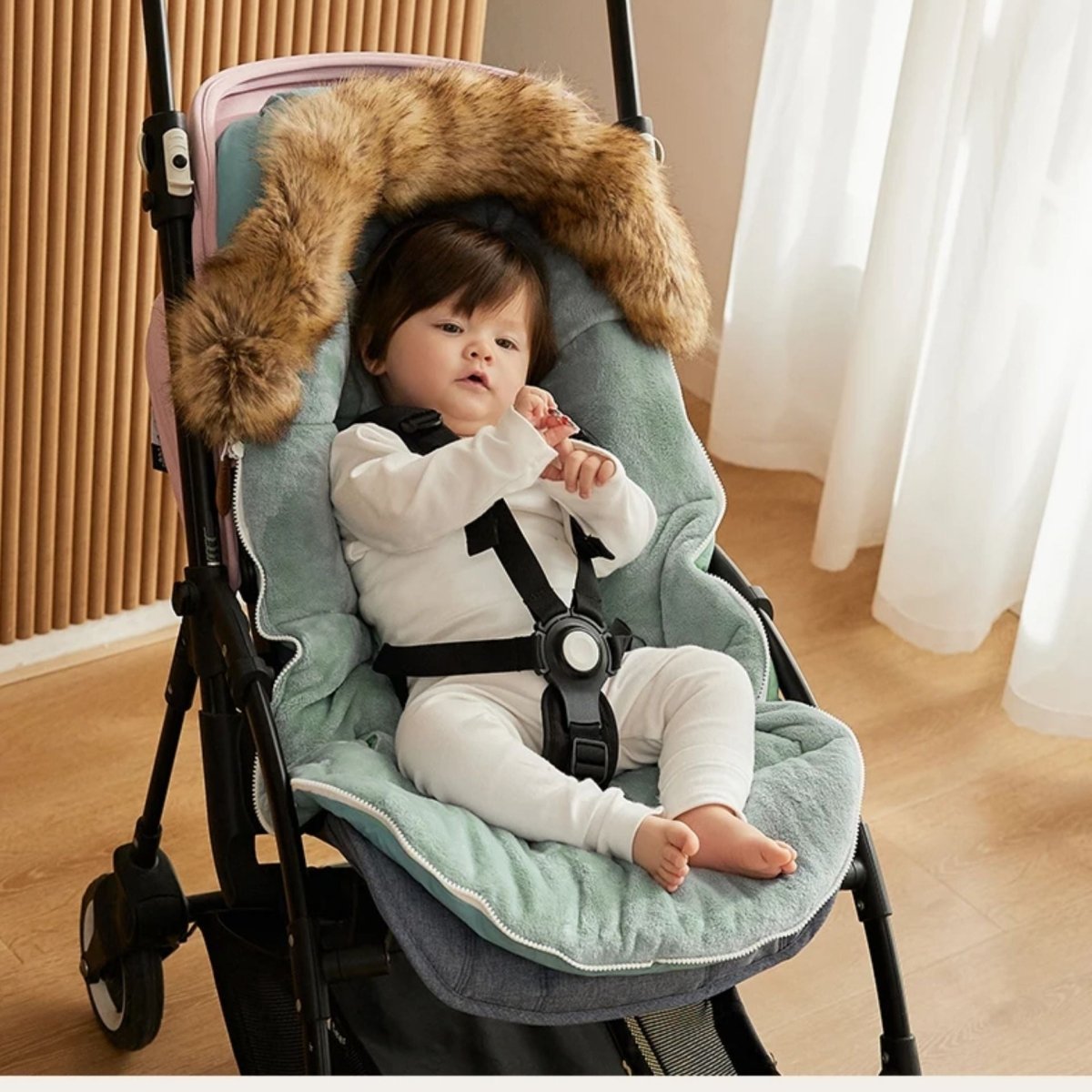 chanceliere bebe ouverte montrant intérieur cocon vert pastel, bébé attaché avec harnais dans la poussette