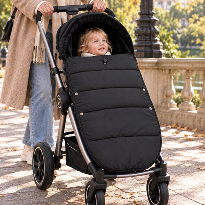 Chancelière noire avec intérieur doux, bébé installé avec sa maman lors d’une promenade en ville
