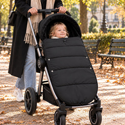 Chancelière noire avec intérieur doux, bébé installé avec sa maman dans un parc