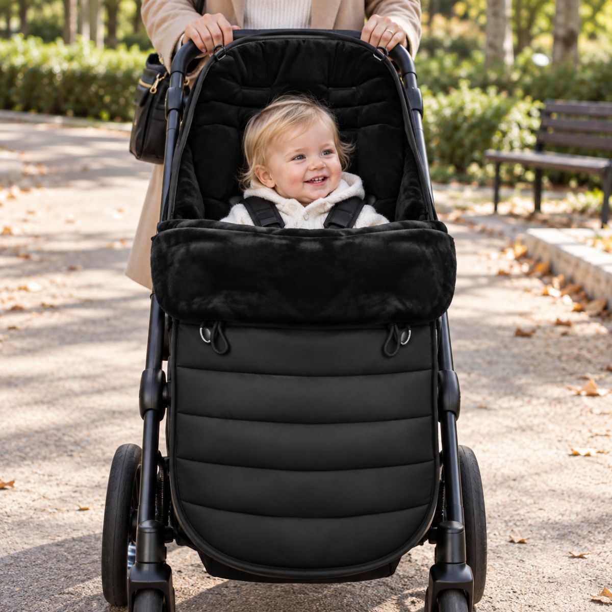 Chancelière évolutive noire installée sur une poussette avec bébé pendant une promenade