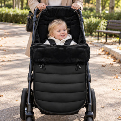 Chancelière évolutive noire installée sur une poussette avec bébé pendant une promenade