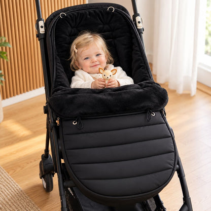 Chancelière évolutive noire avec intérieur doux et bébé installé dans la poussette
