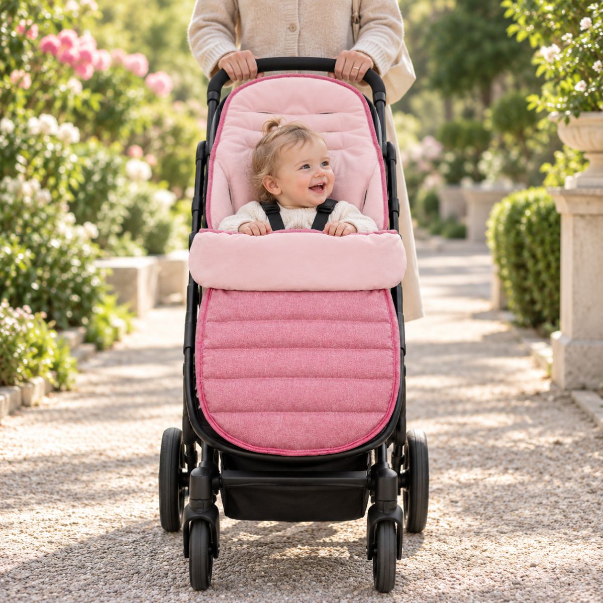 Chancelière évolutive rose installée sur une poussette avec bébé pendant une promenade