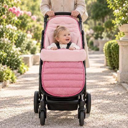 Chancelière évolutive rose installée sur une poussette avec bébé pendant une promenade
