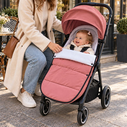 Chanceliere impermeable poussette rose avec bébé installé près d’un café