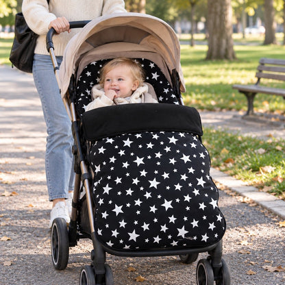 Chancelière polaire noire à étoiles sur poussette avec bébé lors d’une promenade au parc