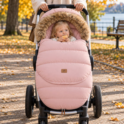 Chancelière poussette rose poudré avec col effet fourrure, bébé installé dans une poussette vue de face en automne