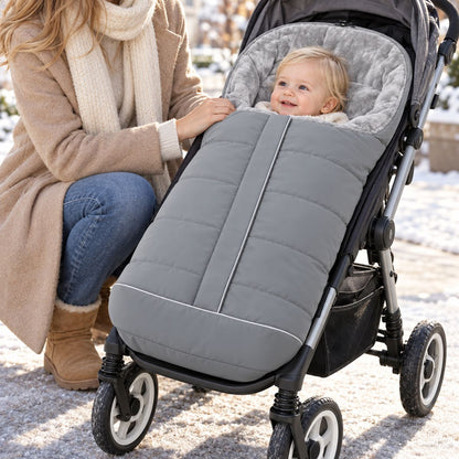 Chancelière poussette gris clair avec doublure polaire grise, bébé installé avec sa maman lors d’une sortie dans la neige