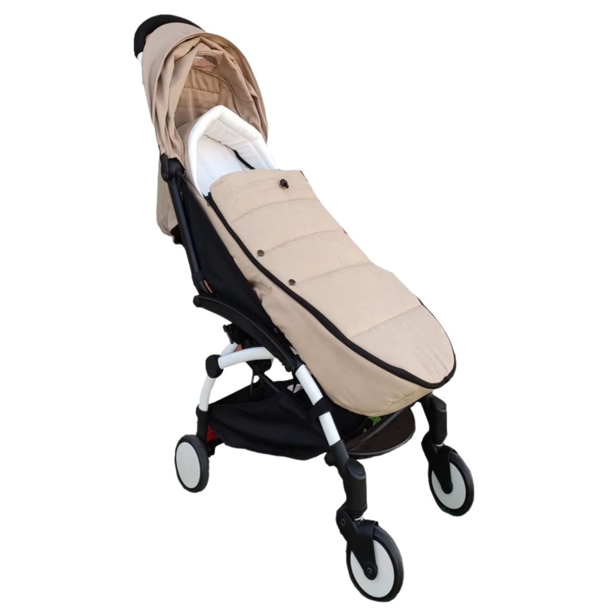 Chancelière poussette beige vue de trois quarts sur poussette blanche en extérieur
