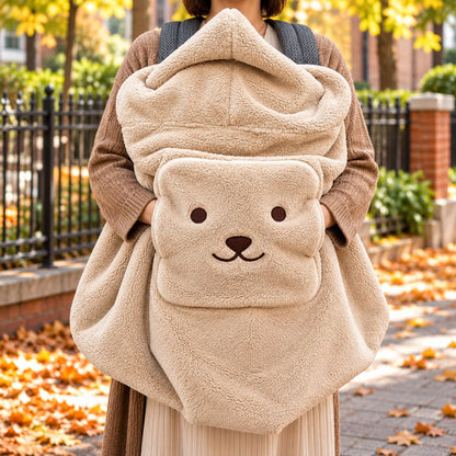 Couverture de portage moumoute beige portée devant une femme, avec texture pelucheuse, grande capuche et poche frontale à visage d’ourson