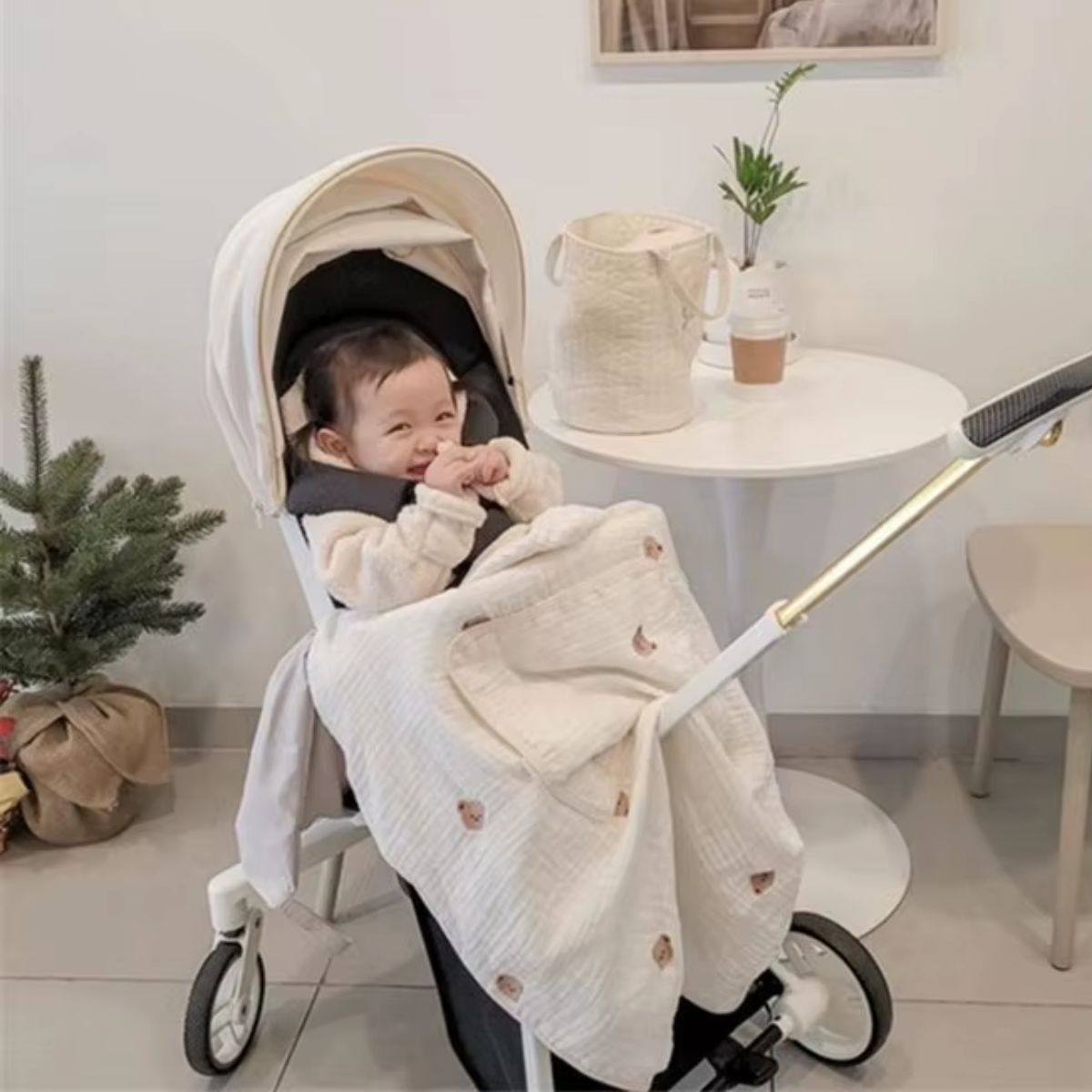 Couverture légère en mousseline à motifs petits ours installée sur une poussette, avec bébé assis
