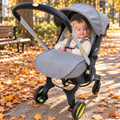 Couvre jambe pour poussette gris avec bébé installé parmi les feuilles d’automne