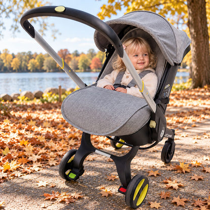 Chancelière poussette Doona grise avec bébé installé lors d’une promenade automnale au bord du lac