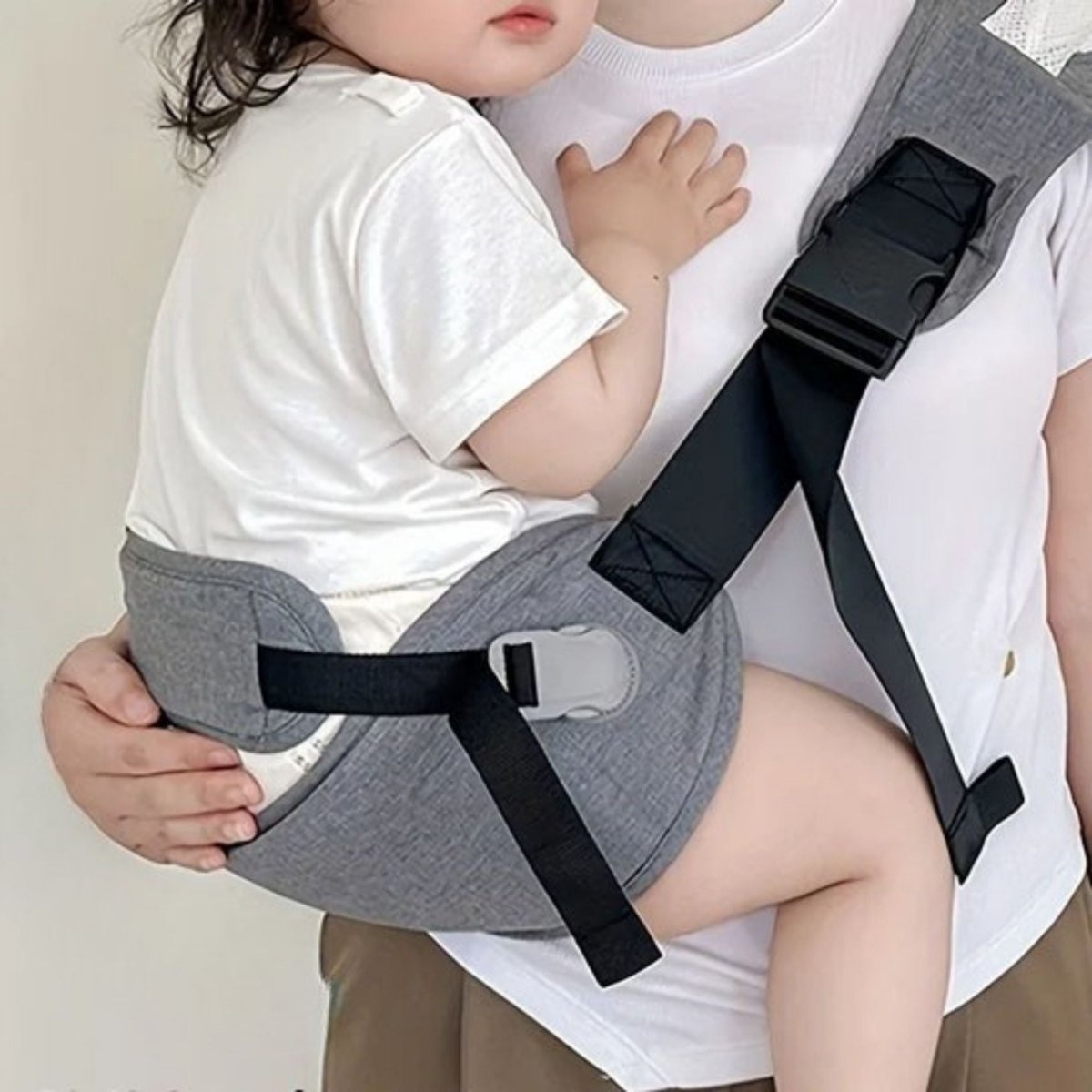 Zoom sur la position assise d’un bébé installé dans une echarpe de portage grise