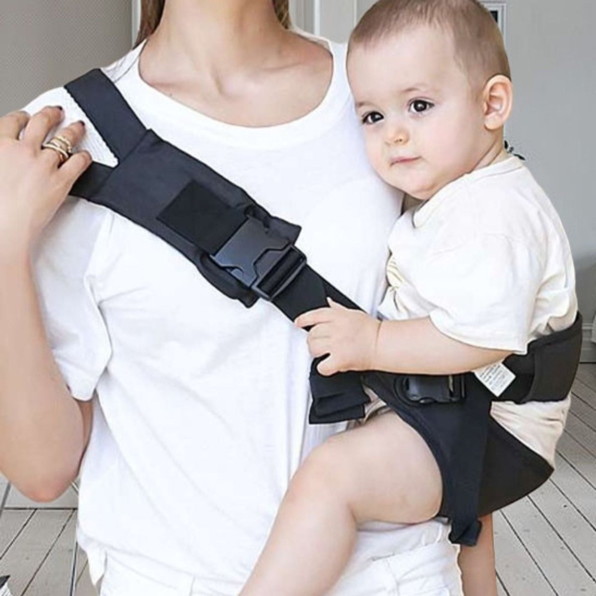 Maman portant son bébé dans une echarpe de portage noire avec boucle renforcée