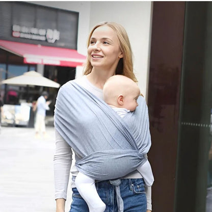 Maman en balade urbaine portant une echarpe de portage gris clair avec bebe