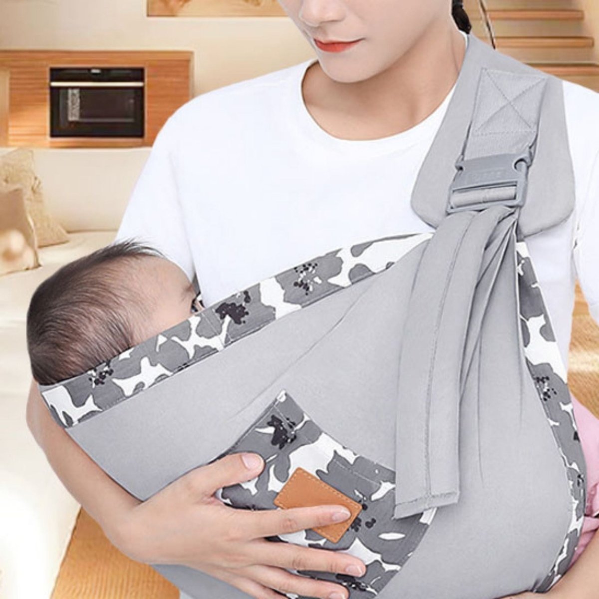 echarpe de portage gris camouflage en intérieur, bébé calé dans la poche côté droit, tissu gris clair avec bord blanc imprimé