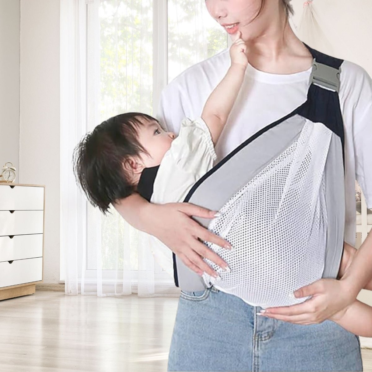 Bébé nourri en position ventrale dans une écharpe grise, intérieur lumineux